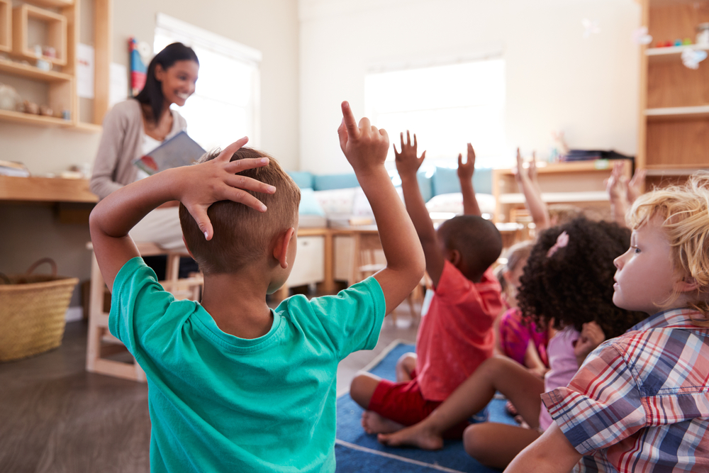 Class of kids with hands raised